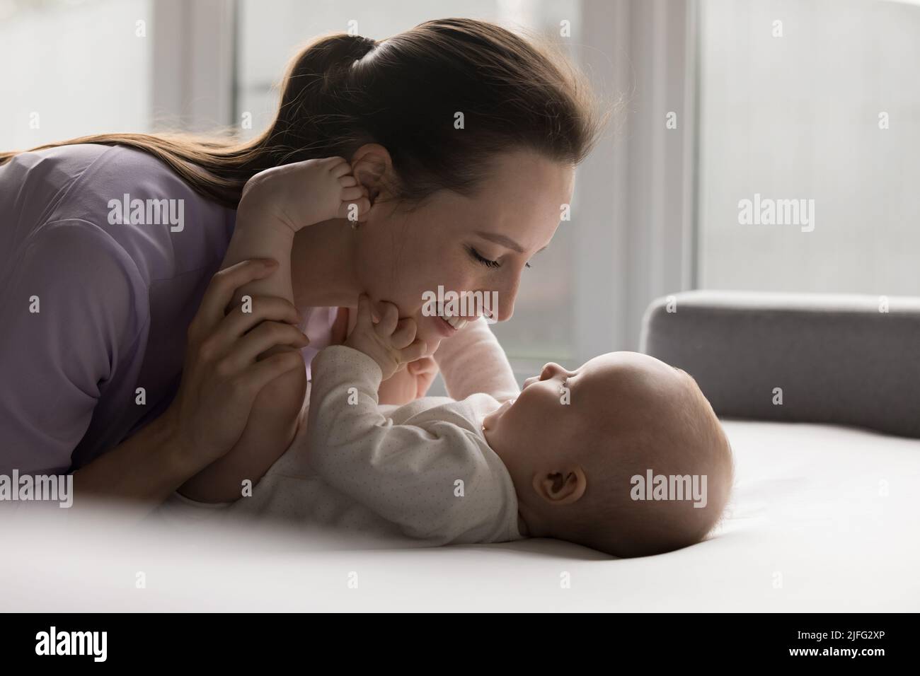 Young beautiful mother spend time with awaken sweet baby Stock Photo