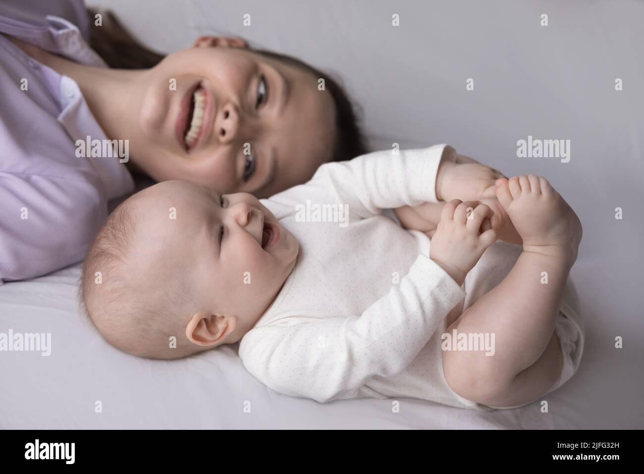 Closeup shot happy adorable baby and mother lying on bed Stock Photo