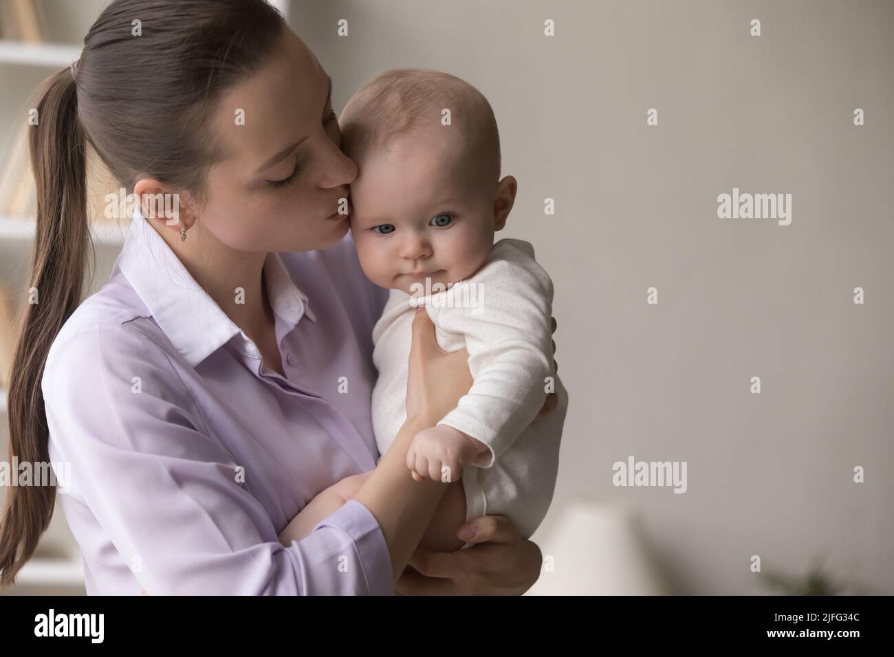 Young loving mother kissing her sweet baby, close up shot Stock Photo
