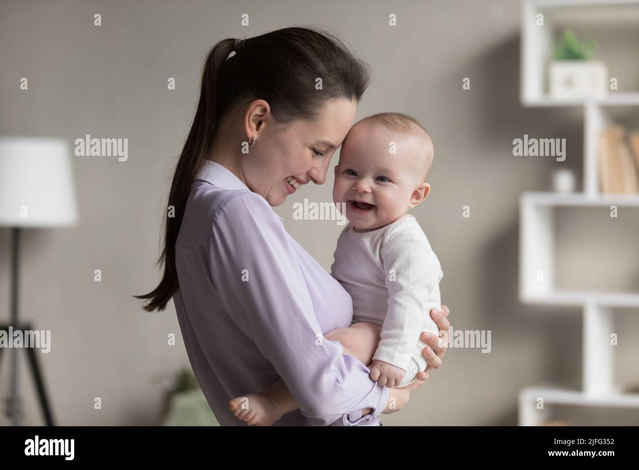 Laughing mother and cheerful adorable newborn child indoor Stock Photo