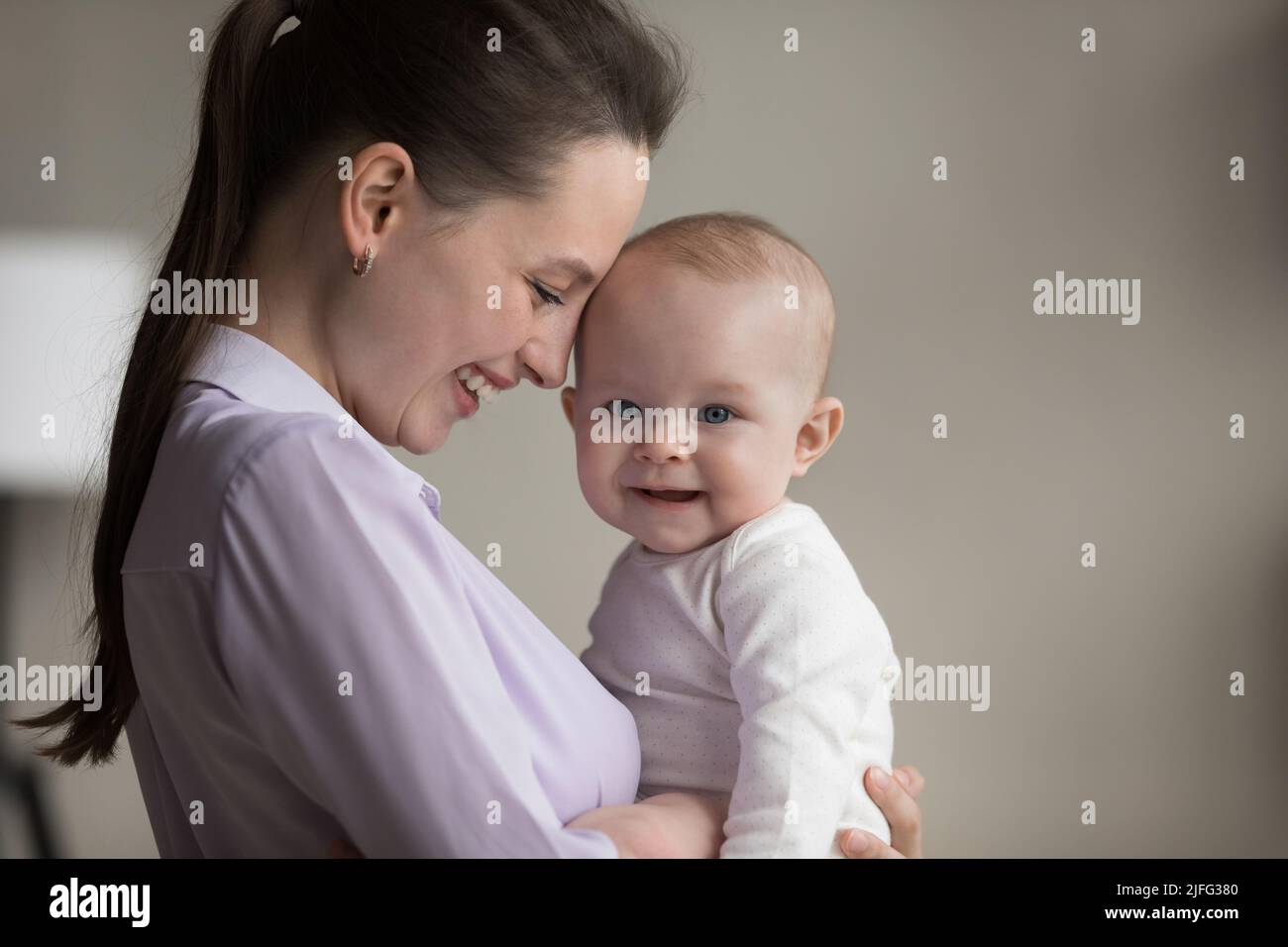 Close up happy young mother and her baby in arms Stock Photo