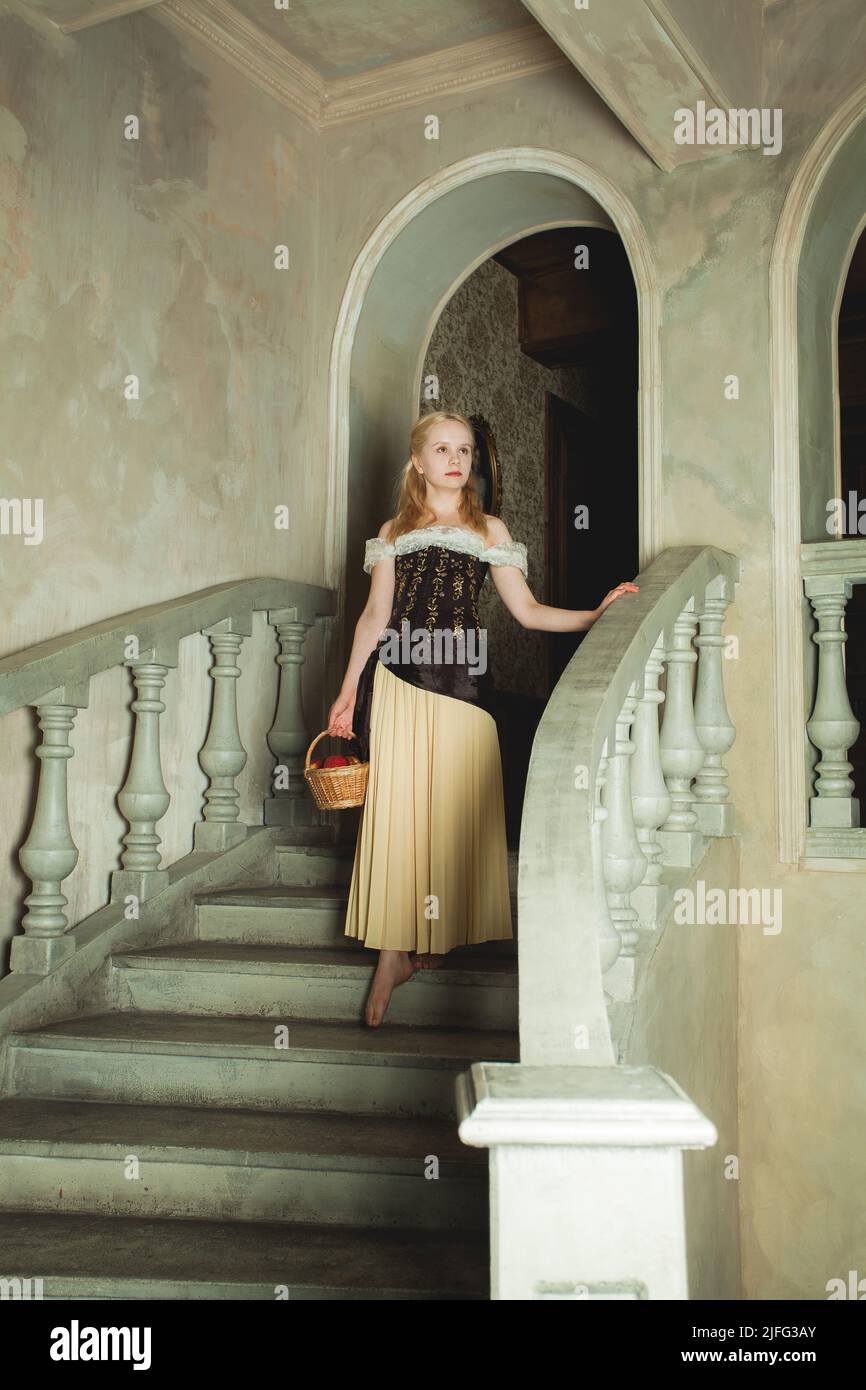 Young blonde woman wearing retro dress going down vintage stairs Stock Photo