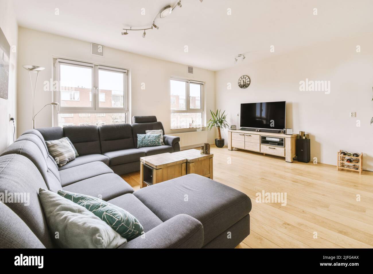 Simple interior of light living room with gray sofa in front of TV and