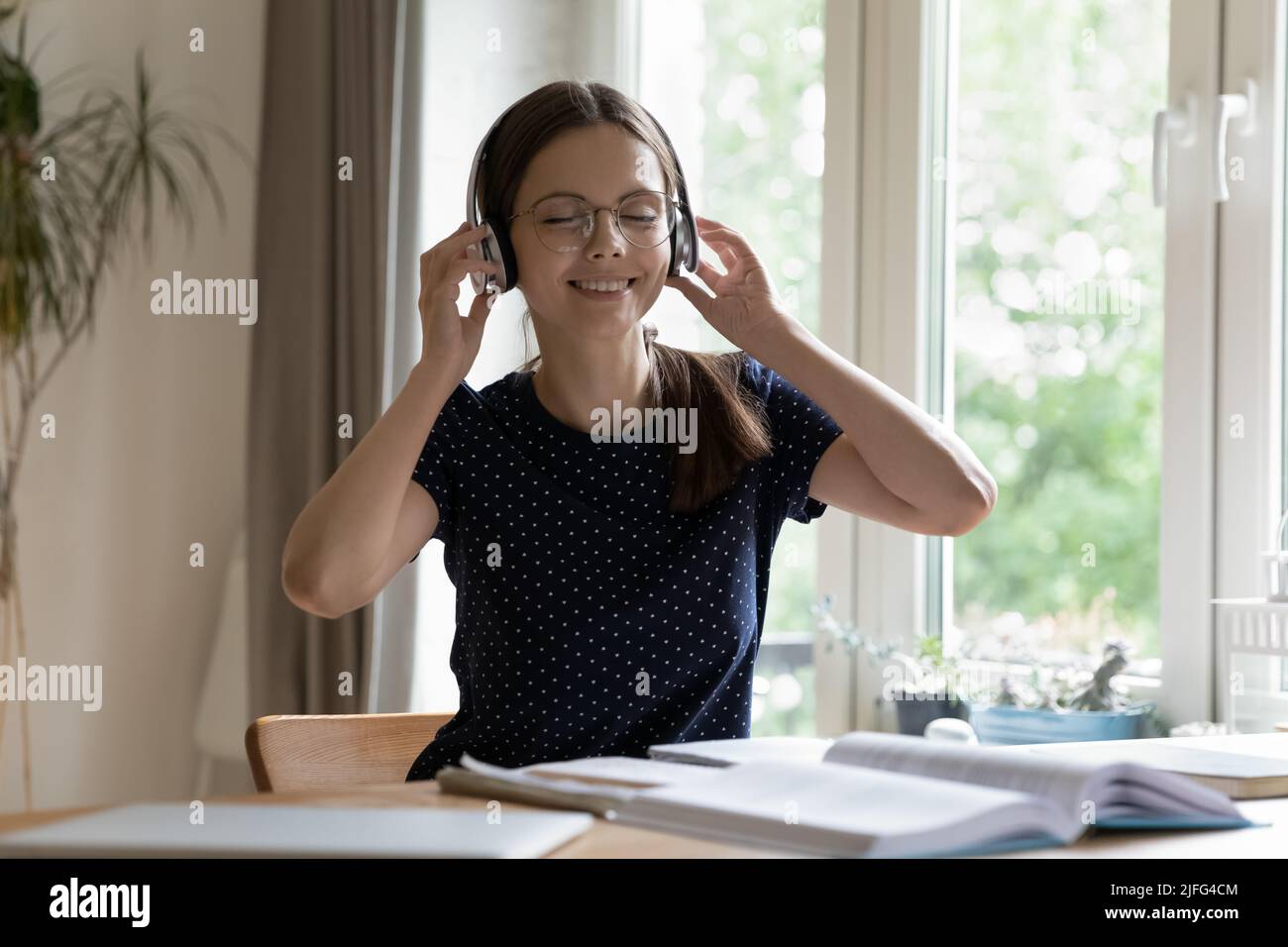 Happy satisfied student girl in eyeglasses, wireless headphones enjoying music Stock Photo