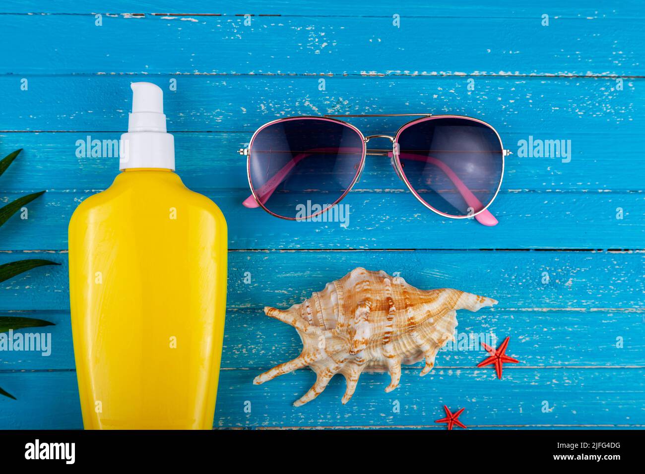 Flat lay composition with sunscreen and seashells on a blue wooden background. Stock Photo