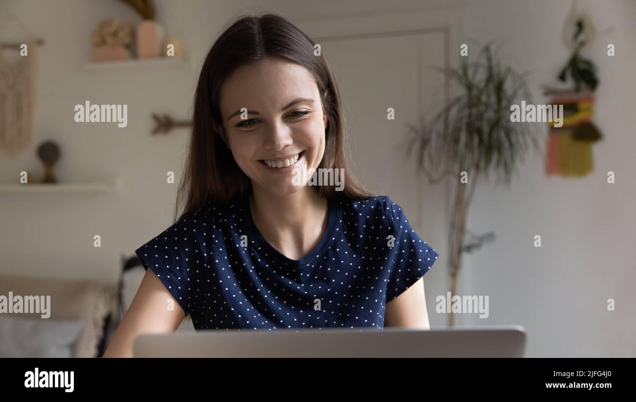 Positive happy young freelancer woman using laptop at home Stock Photo