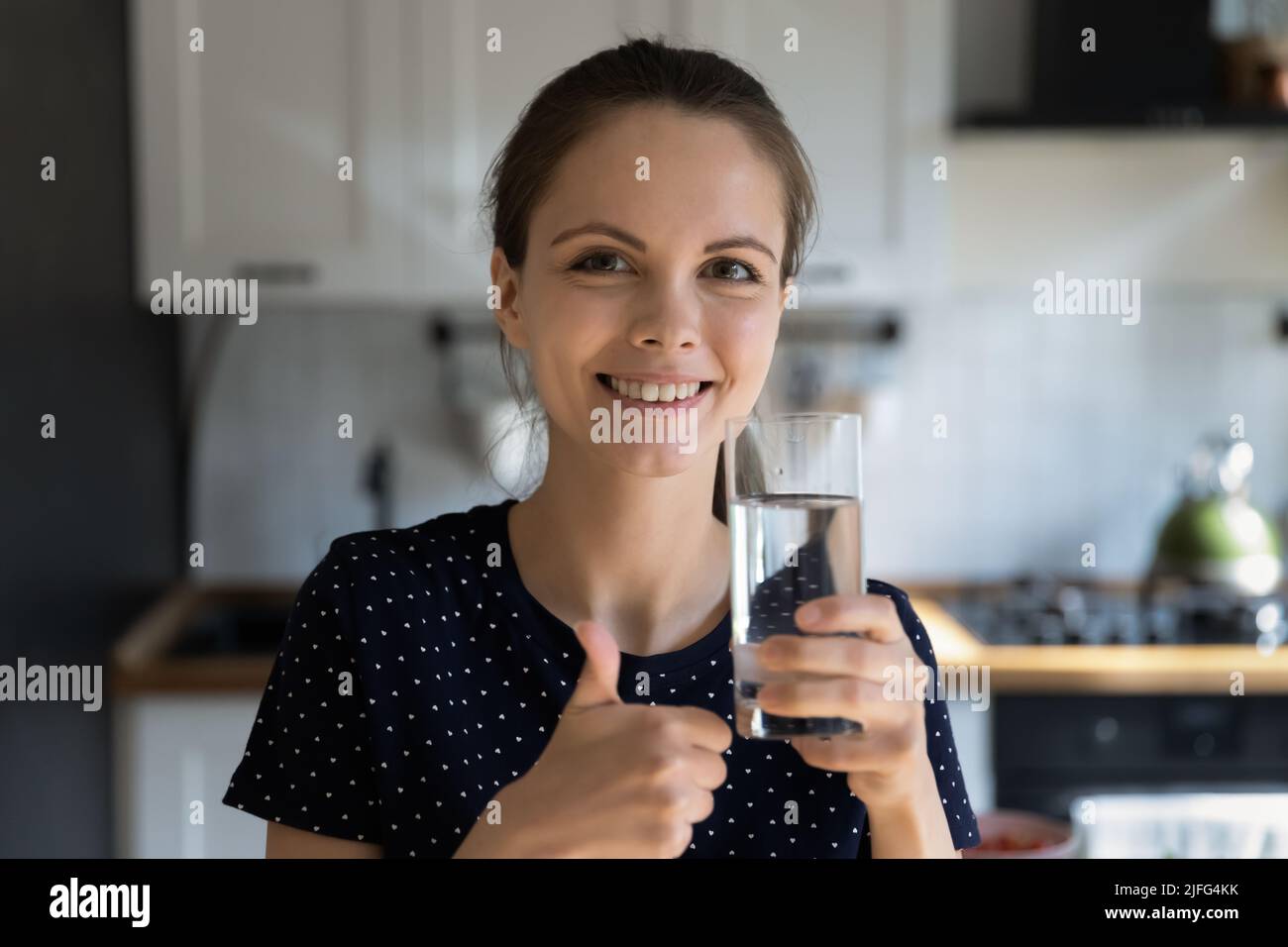 Happy beautiful girl drinking fresh water in home kitchen Stock Photo