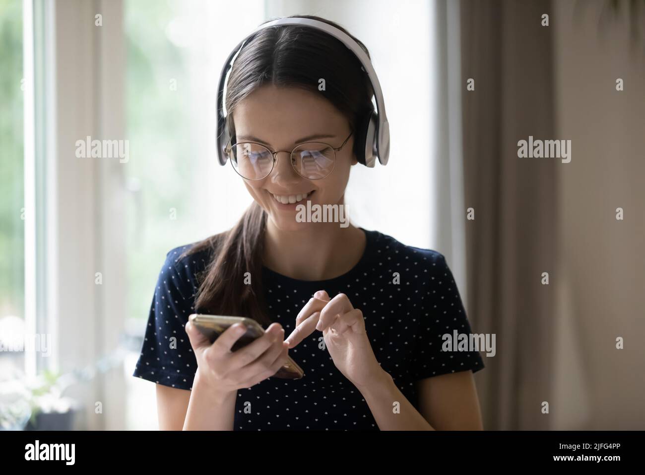 Cheerful young girl in wireless headphones listening to music Stock ...