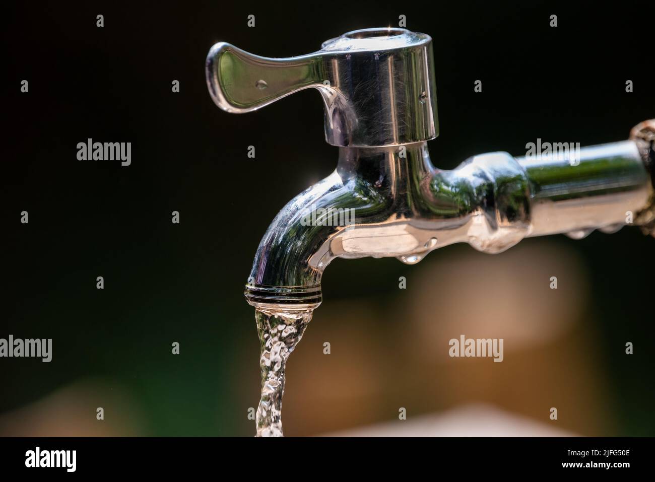 Outdoor chrome faucet running water close-up view Stock Photo