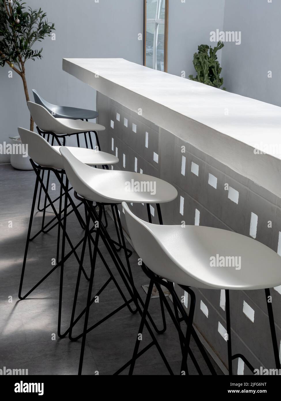 Empty white bar stool chairs. Row of modern seats at white concrete bar counter decoration in
