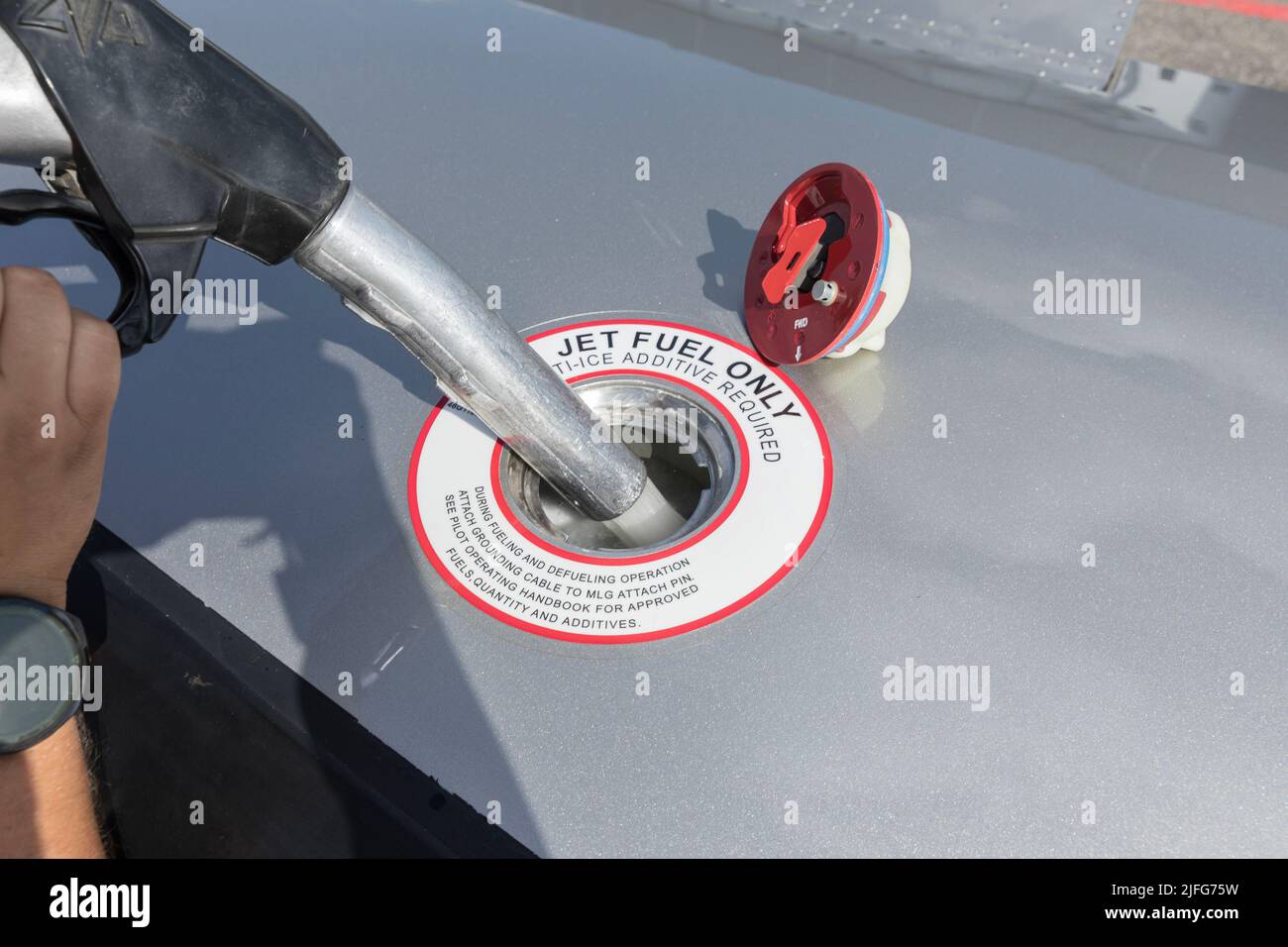 A close-up view of the aircraft's fuel tank, fuel is being filled into the tank. Fuel nozzle filling up aircraft, refueling jet fuel in an aircraft wi Stock Photo