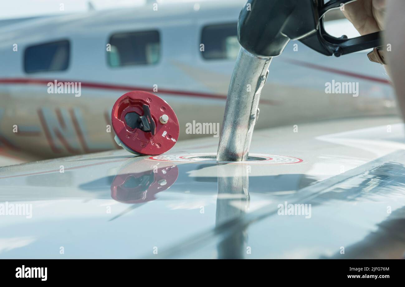 A close-up view of the aircraft's fuel tank, fuel is being filled into the tank. Fuel nozzle filling up aircraft, refueling jet fuel in an aircraft wi Stock Photo