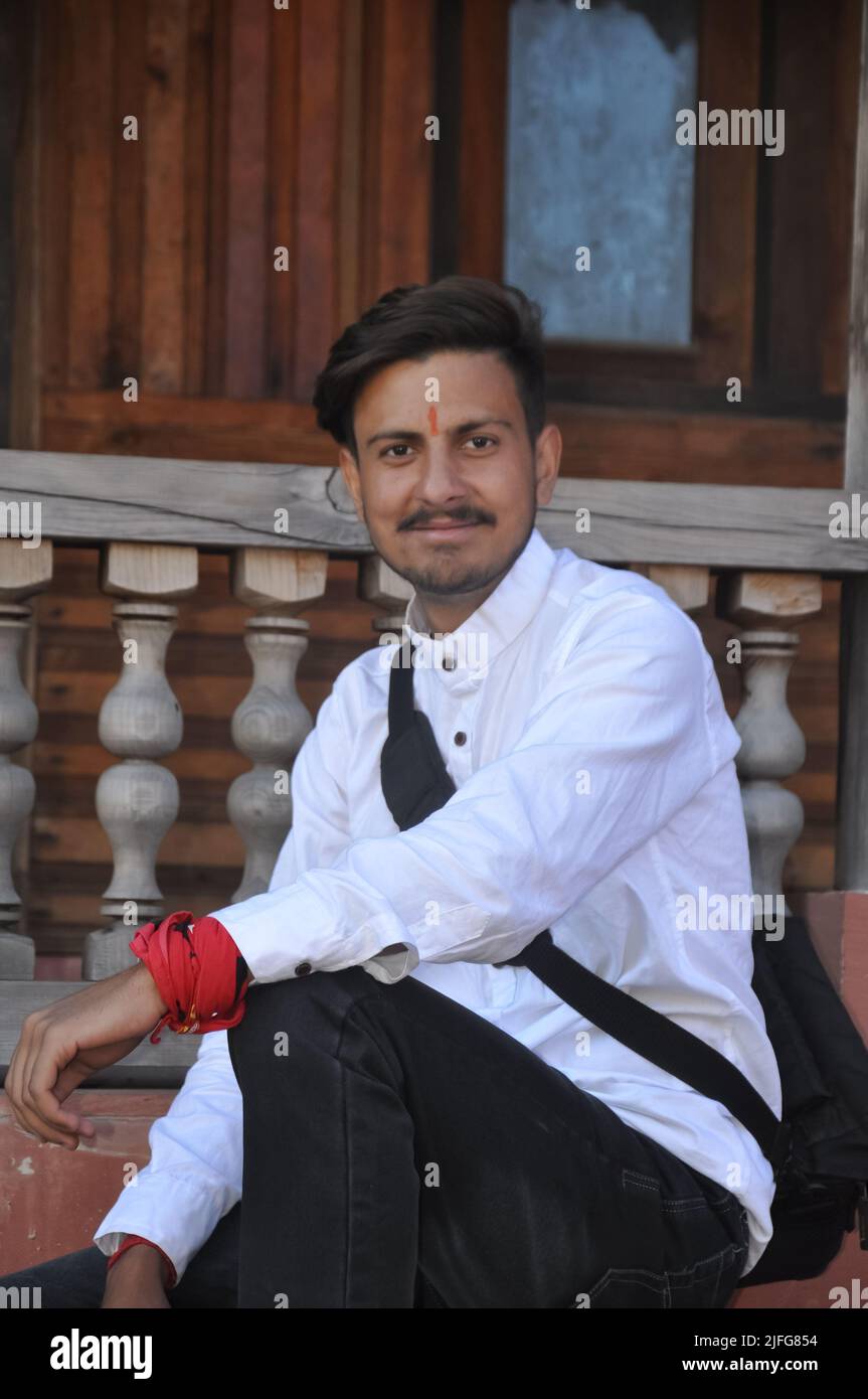 A happy young guy looking at camera while sitting on temple stairs Stock Photo