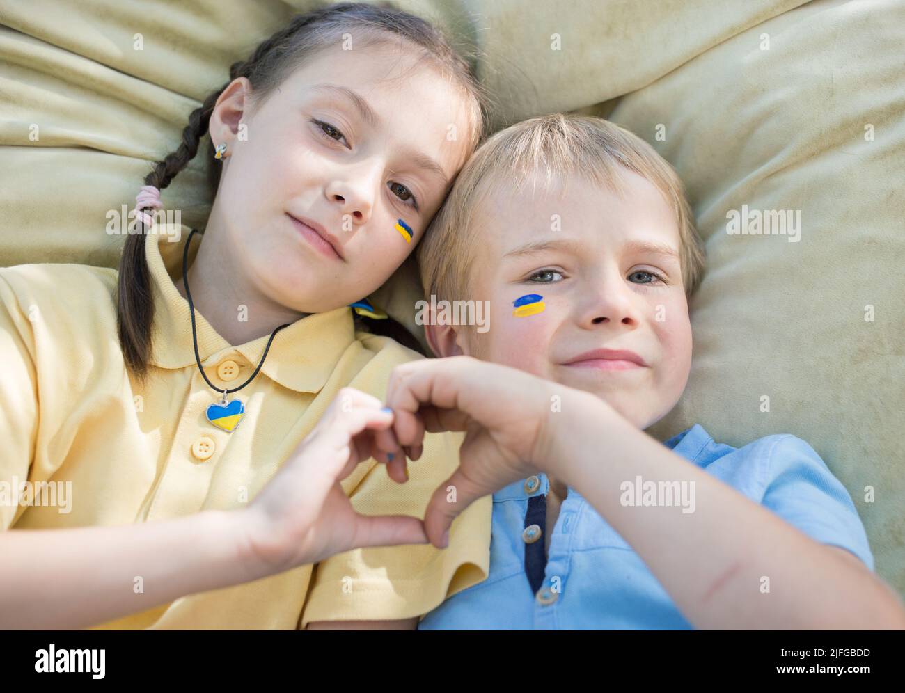 civilians, Ukrainian children, refugees, a boy and a girl in a yellow and blue T-shirt, with their hands folded in the shape of a heart. family, unity Stock Photo
