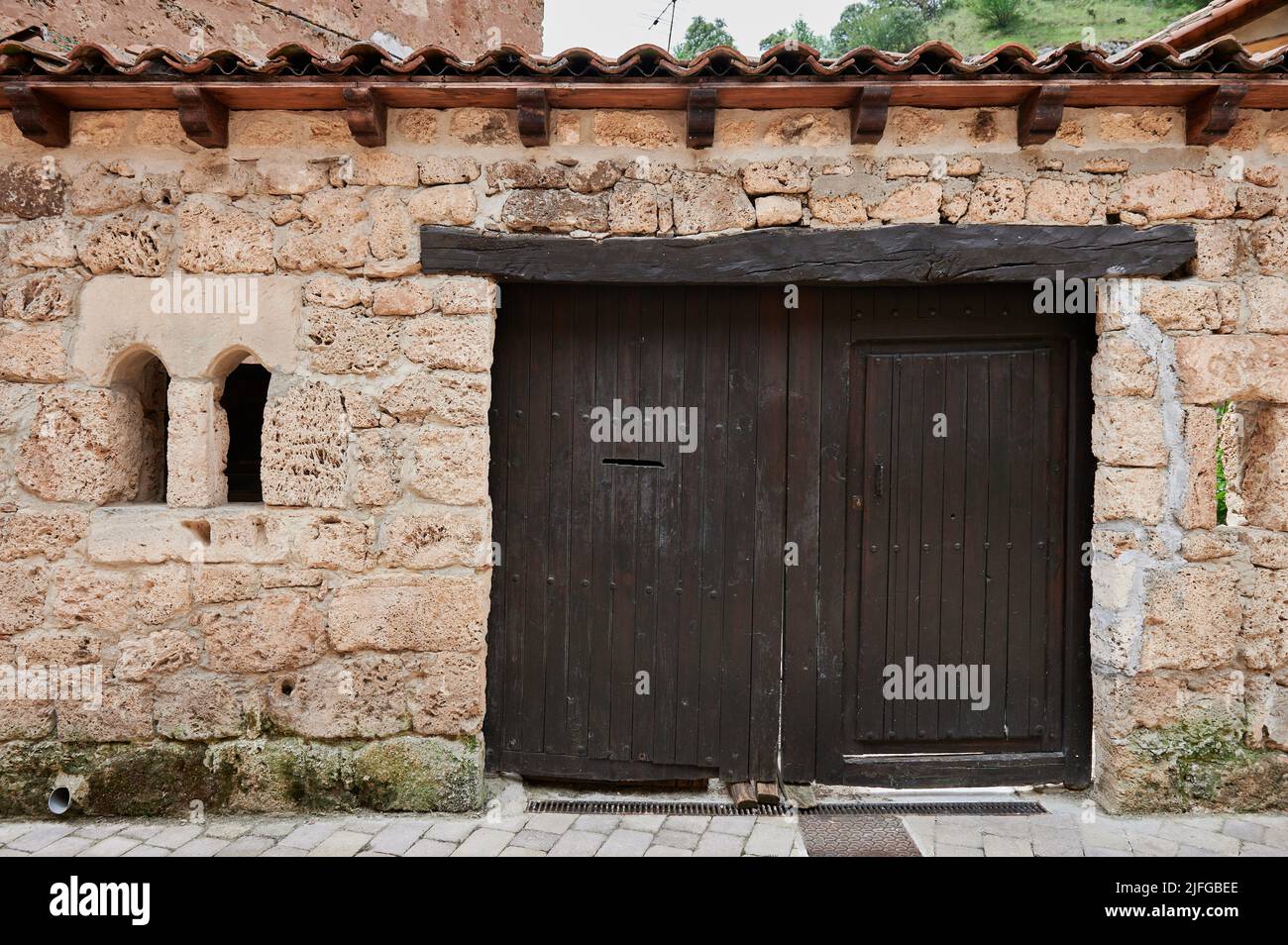 Stone facade with small old wooden door at little town of Orbaneja del Castillo, Burgos, Spain, Europe Stock Photo