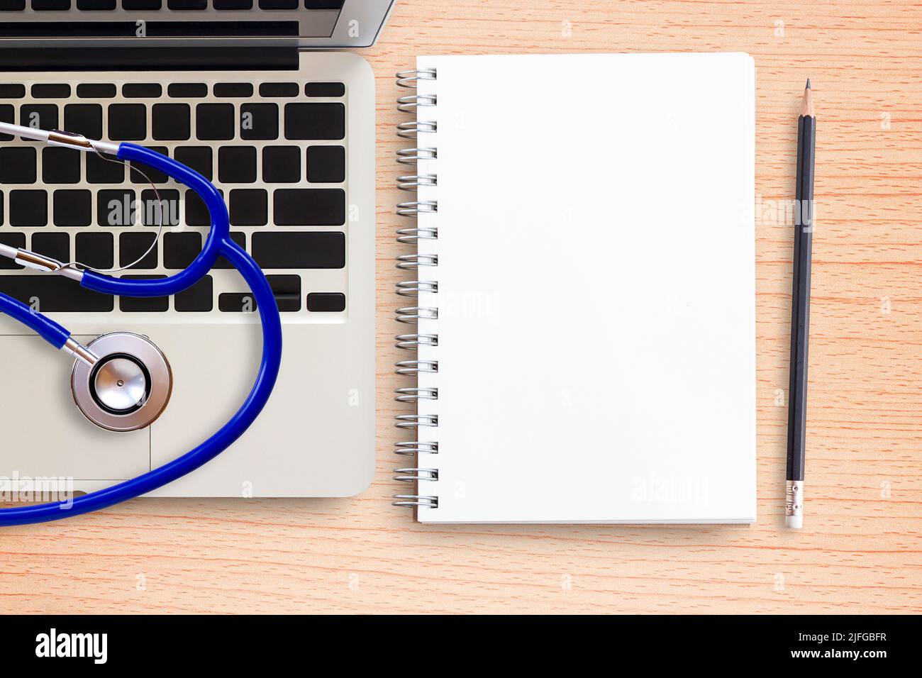 Laptop computer, stethoscope and notebook on office desk wooden table ...