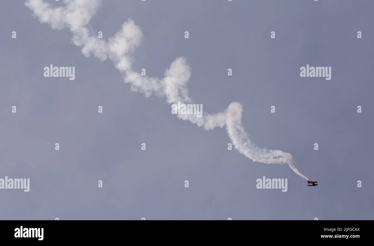 A scenic view of a biplane aircraft doing a corkscrew maneuver in the