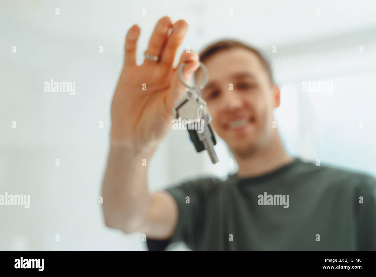 Satisfied homeowner. portrait of happy young man buyer renter of new modern home apartment holding key dwelling demonstrating wellbeing wealth celebra Stock Photo