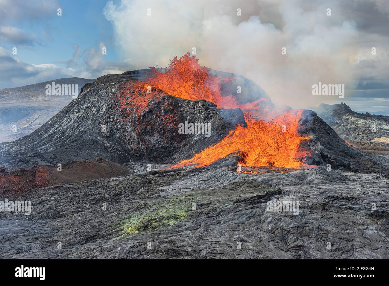 Volcano on Iceland's Reykjanes Peninsula. Lava fountains from the volcanic crater. Landscape in spring with sunshine. Liquid lava flows out of the sid Stock Photo