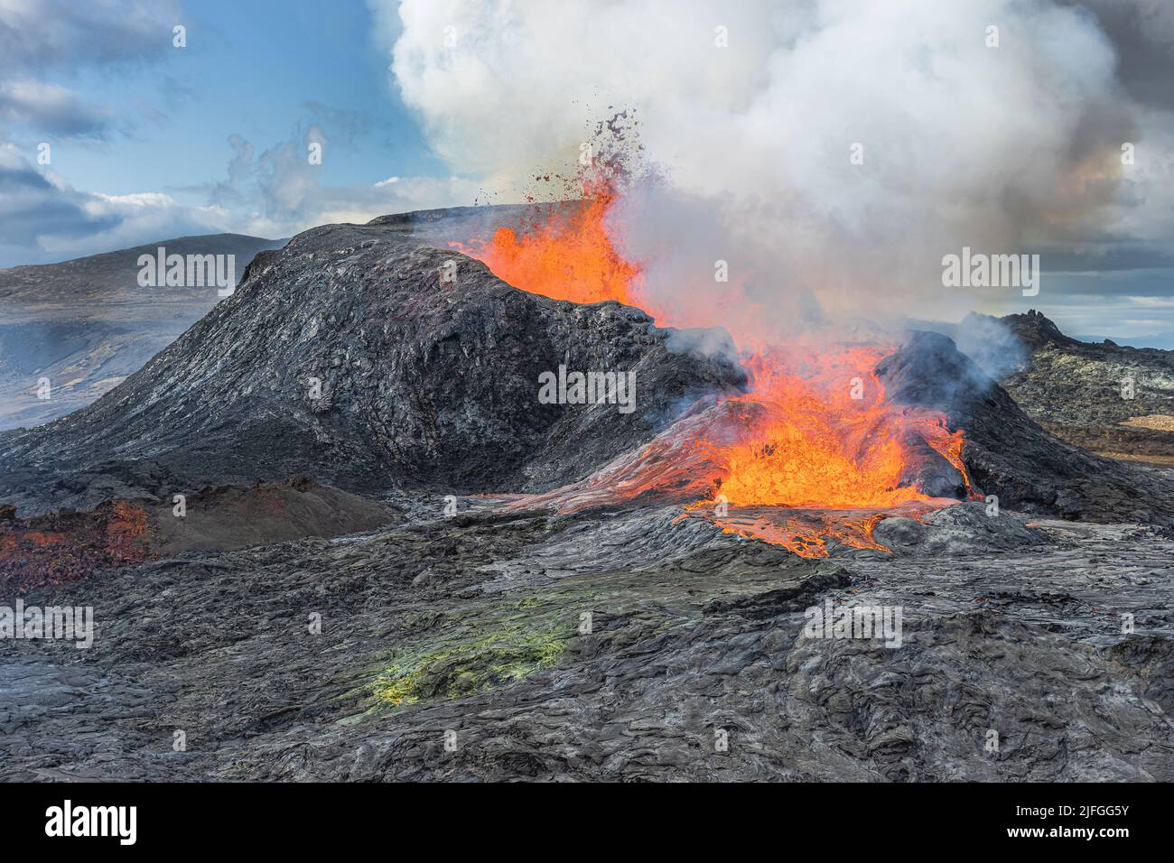 Volcano eruption in Iceland. active volcano with lava fountain. Lateral outflow of the hot reddish lava. View of volcano in the day with sunshine. clo Stock Photo