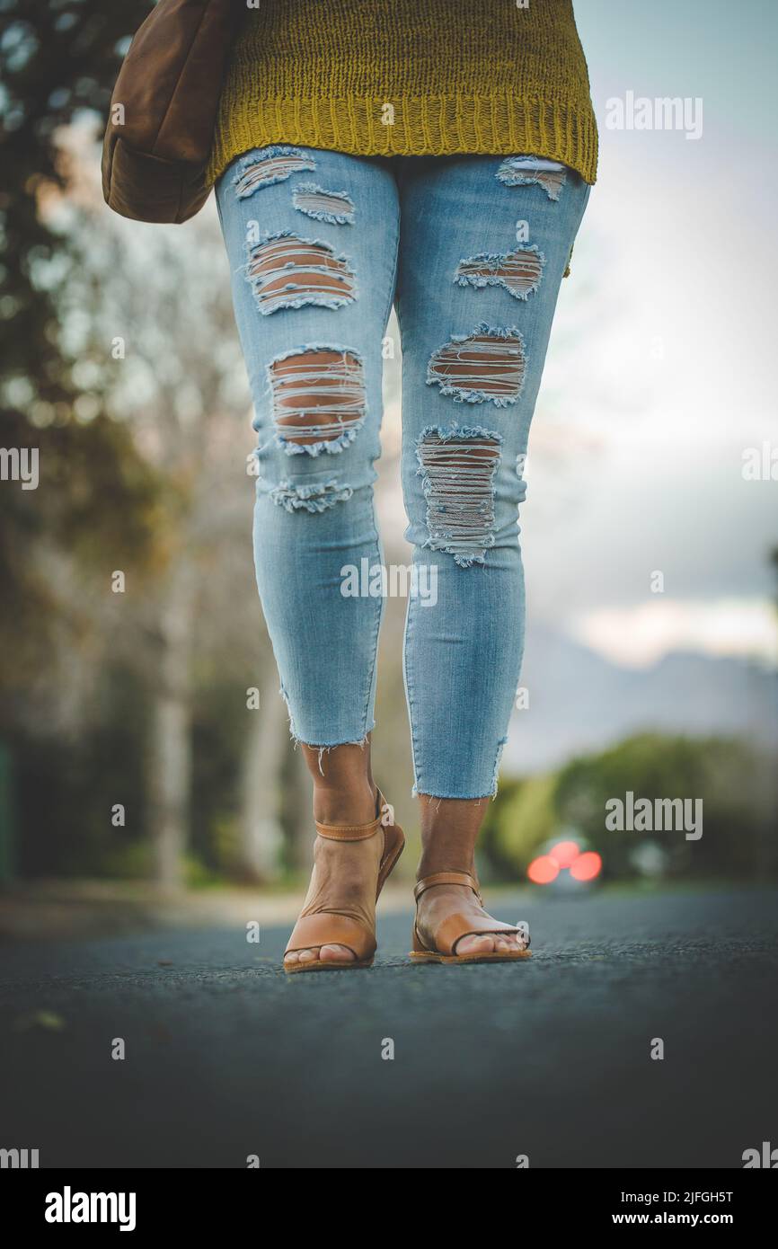 female legs wearing blue ripped jeans 
