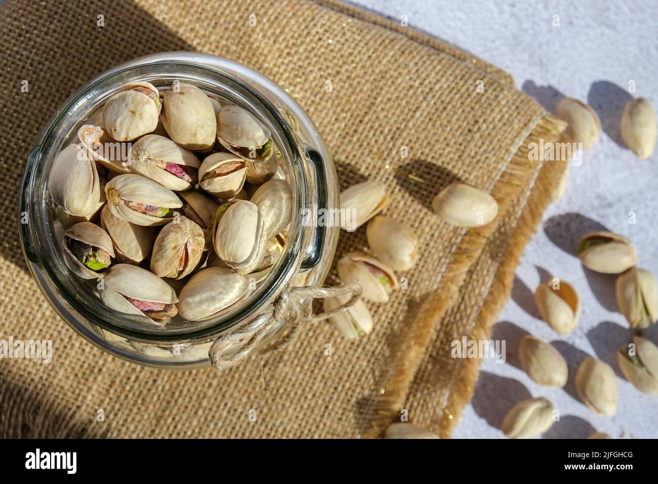 Pistachios in glass jar on concrete background. Organic pistachios