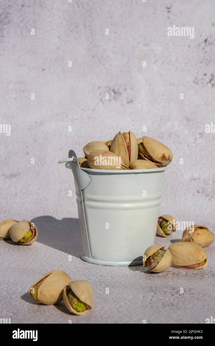 Pistachios in white bucket on concrete background. Healthy and dietary