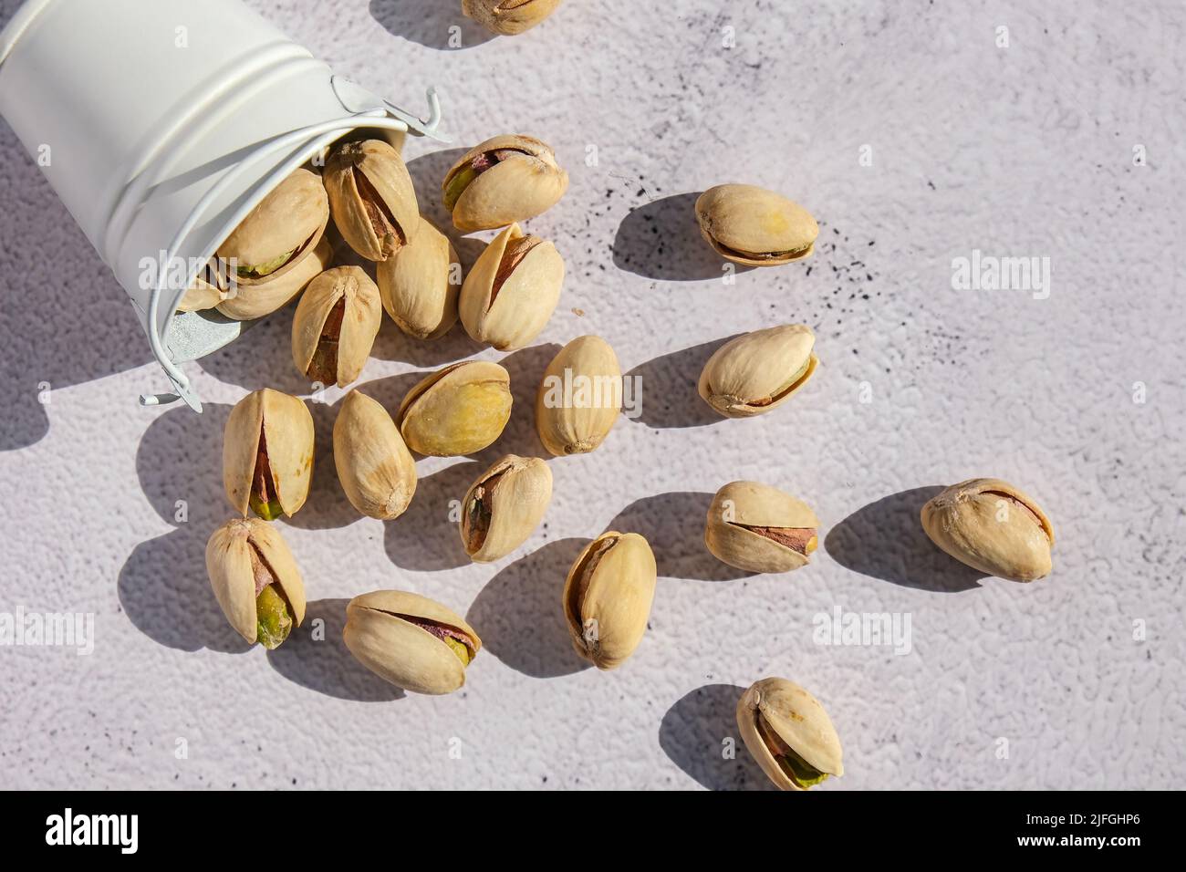 Pistachios in white bucket on concrete background. Healthy and dietary