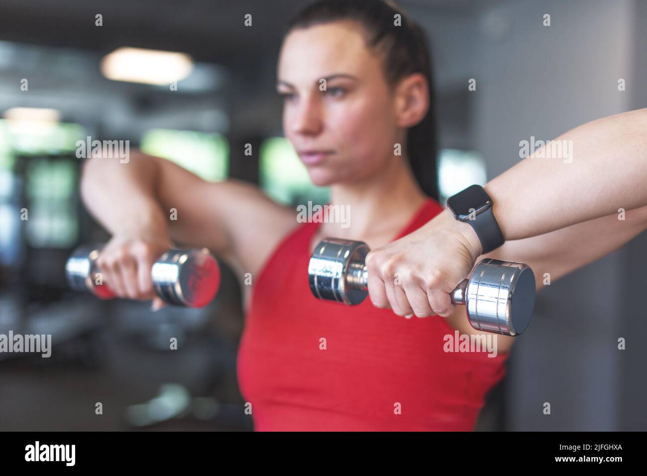 Young woman doing exercise with dumbbells portrait, depth of field Stock Photo