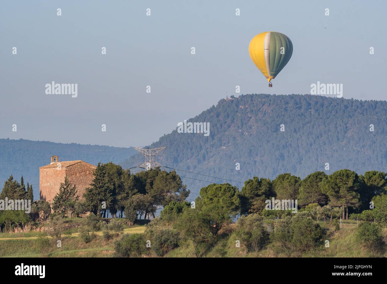 hot air balloon flying over church,  Santpedor, Catalonia, Spain Stock Photo