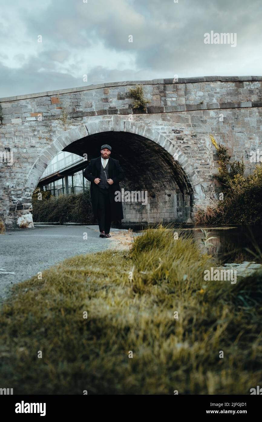 stylish gangster man walking thru a tunnel under a railway bridge 1920s