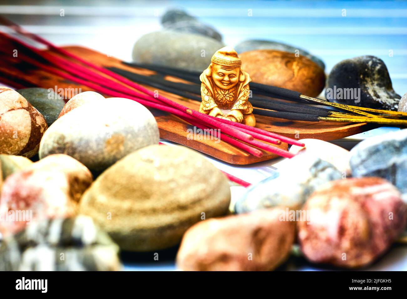 Statuette of a Buddhist monk among incense and various stones Stock Photo