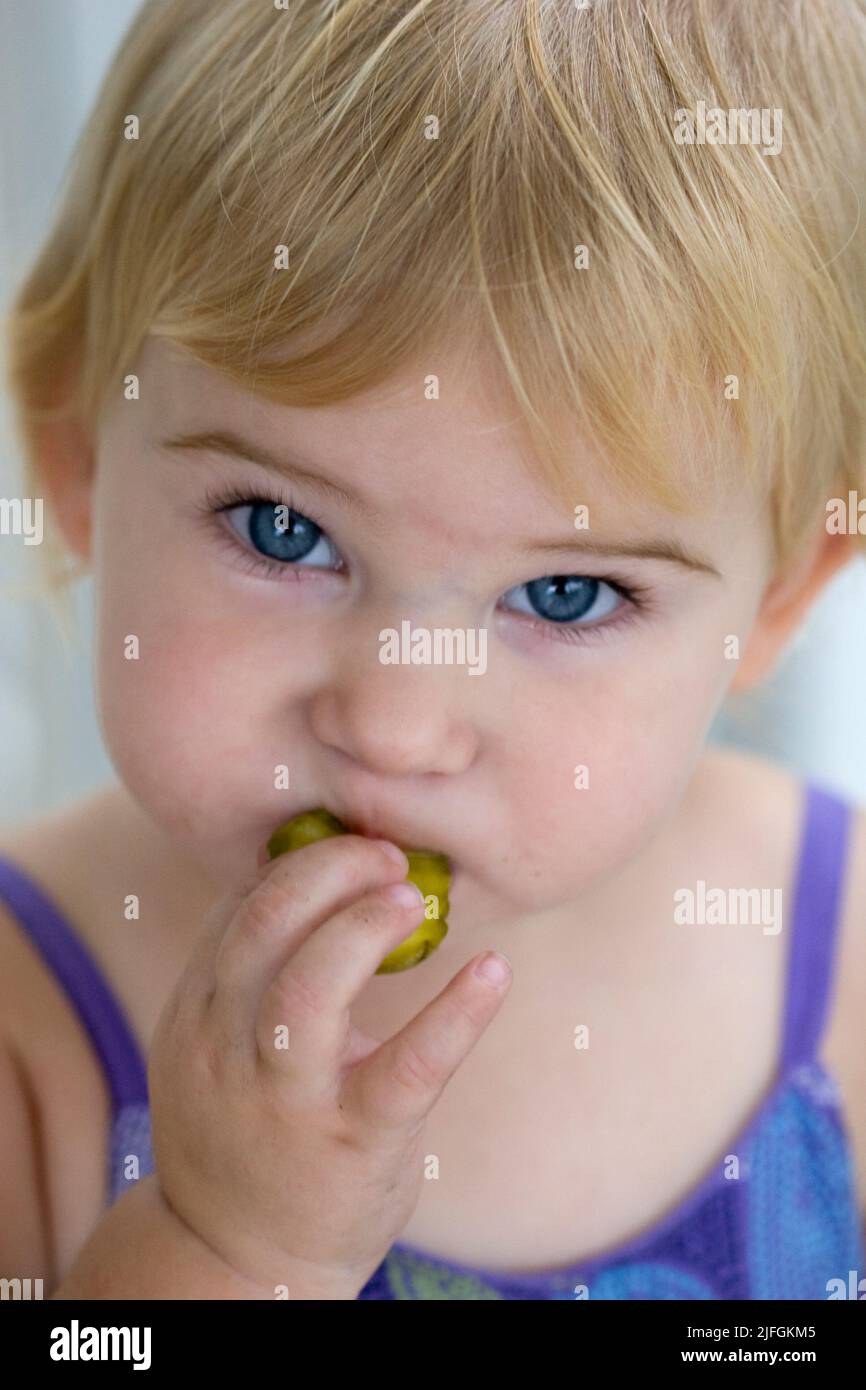 15 month old girl eating a pickle Stock Photo
