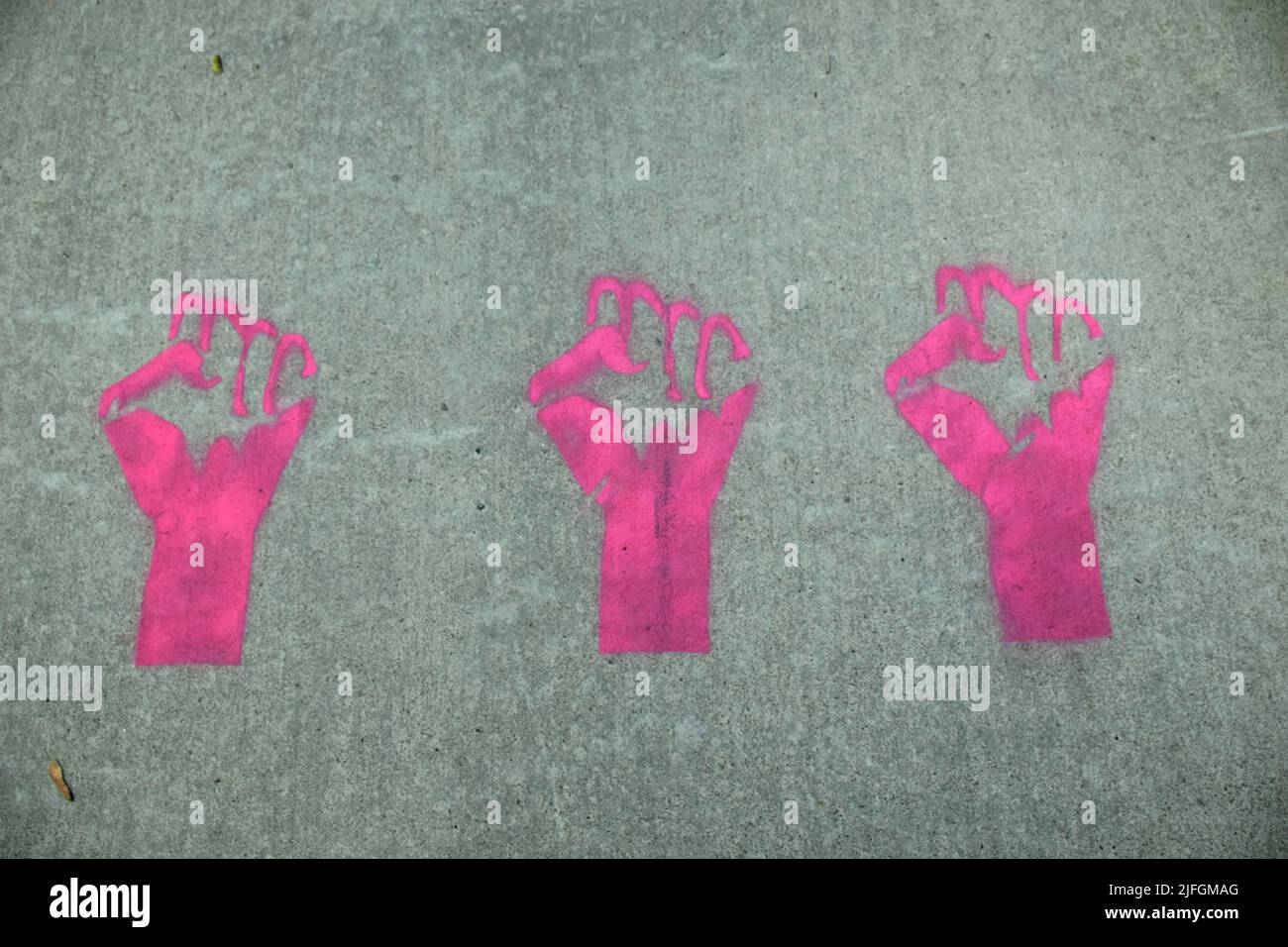 Three fists painted on sidewalk Stock Photo