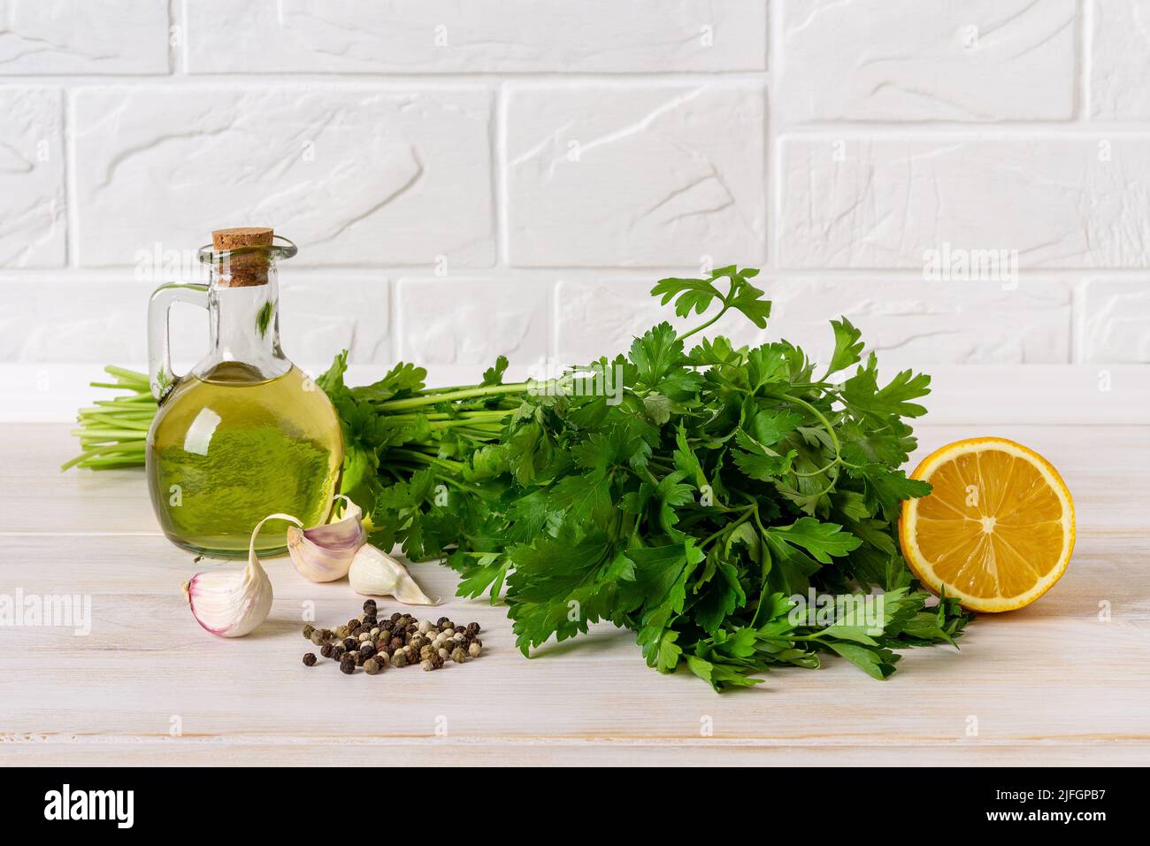 Green sauce ingredients. Salsa verde from fresh parsley, garlic cloves, olive oil and lemon juice. Homemade chimichurri dipping sauce recipe. Stock Photo