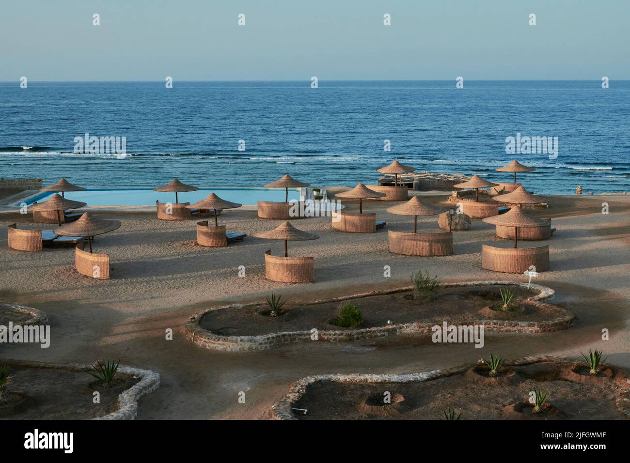 Evening Mood Picture Of A Bathing Beach With Parasols, Windbreak And Pool. In The Background Ocean And Blue Sky. Marsa Alam, Egypt Stock Photo