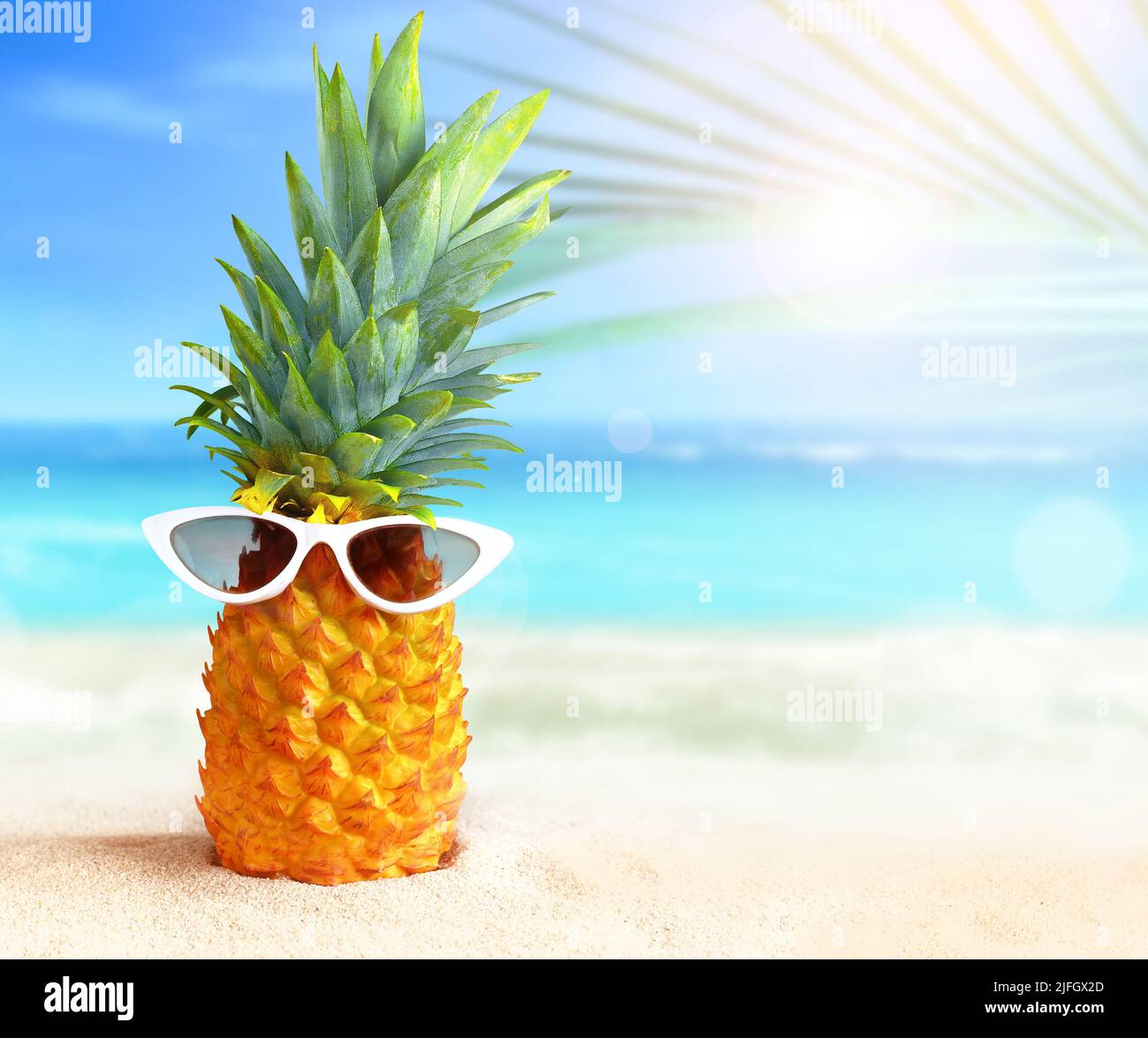 Pineapple with sunglasses on tropical beach background. Summer concept