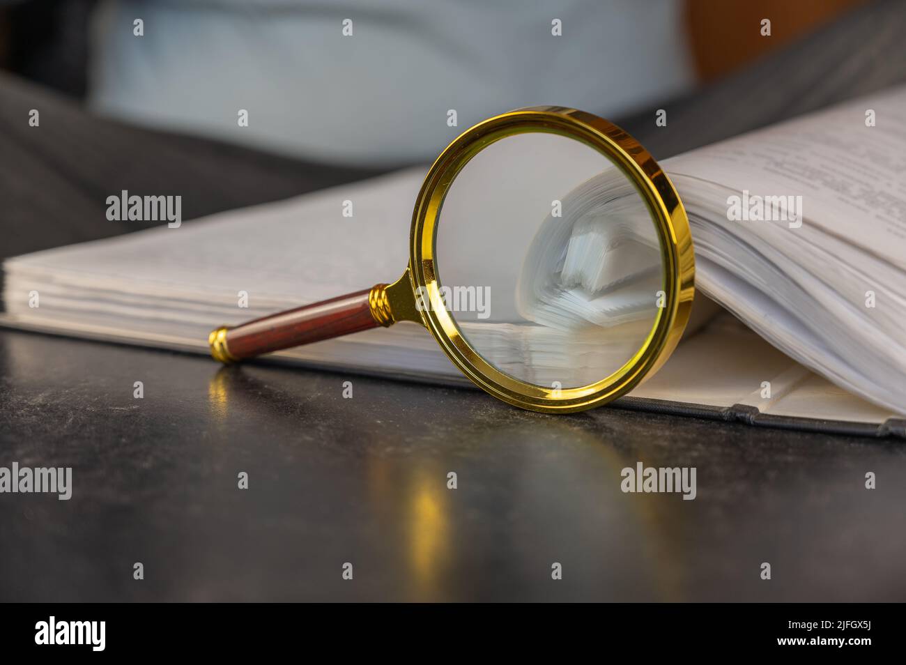 A magnifying glass next to an open file folder. Gray file folder with ...