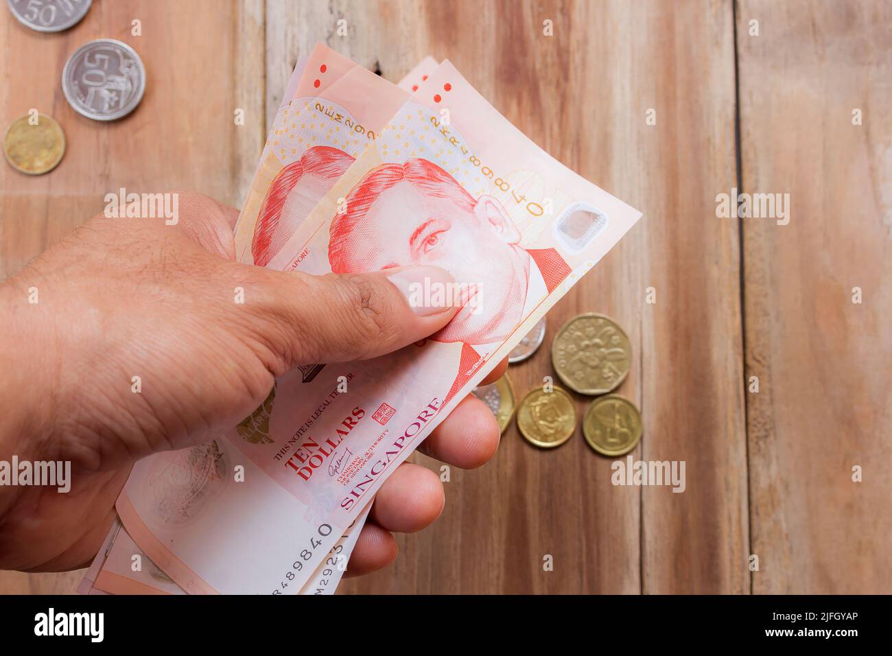 Hand holding Singapore money on wooden table background, various of singapore  dollar banknote Stock Photo - Alamy
