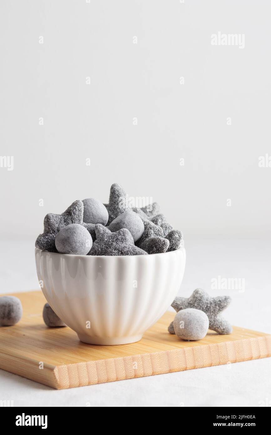 Salty liquorice salmiakki in Finnish in a white bowl and a wooden
