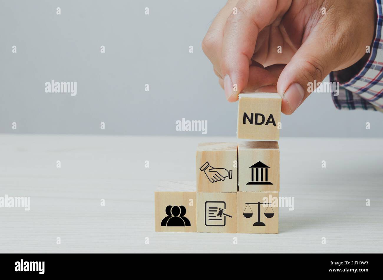 Hand put wooden cubes with Non disclosure Agreement NDA on table and ...