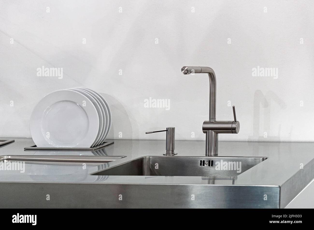 Modern kitchen faucet at stainless steel sink with built in dish dryer