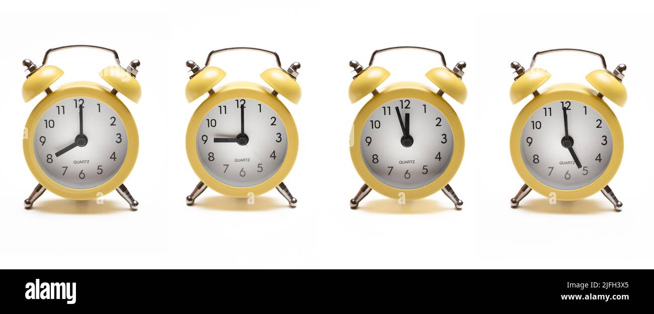 Wake up concept. Four yellow vintage alarm clock isolated cutout on white background. Metal circular alarm clock with bubble ring bell with misc time. Stock Photo