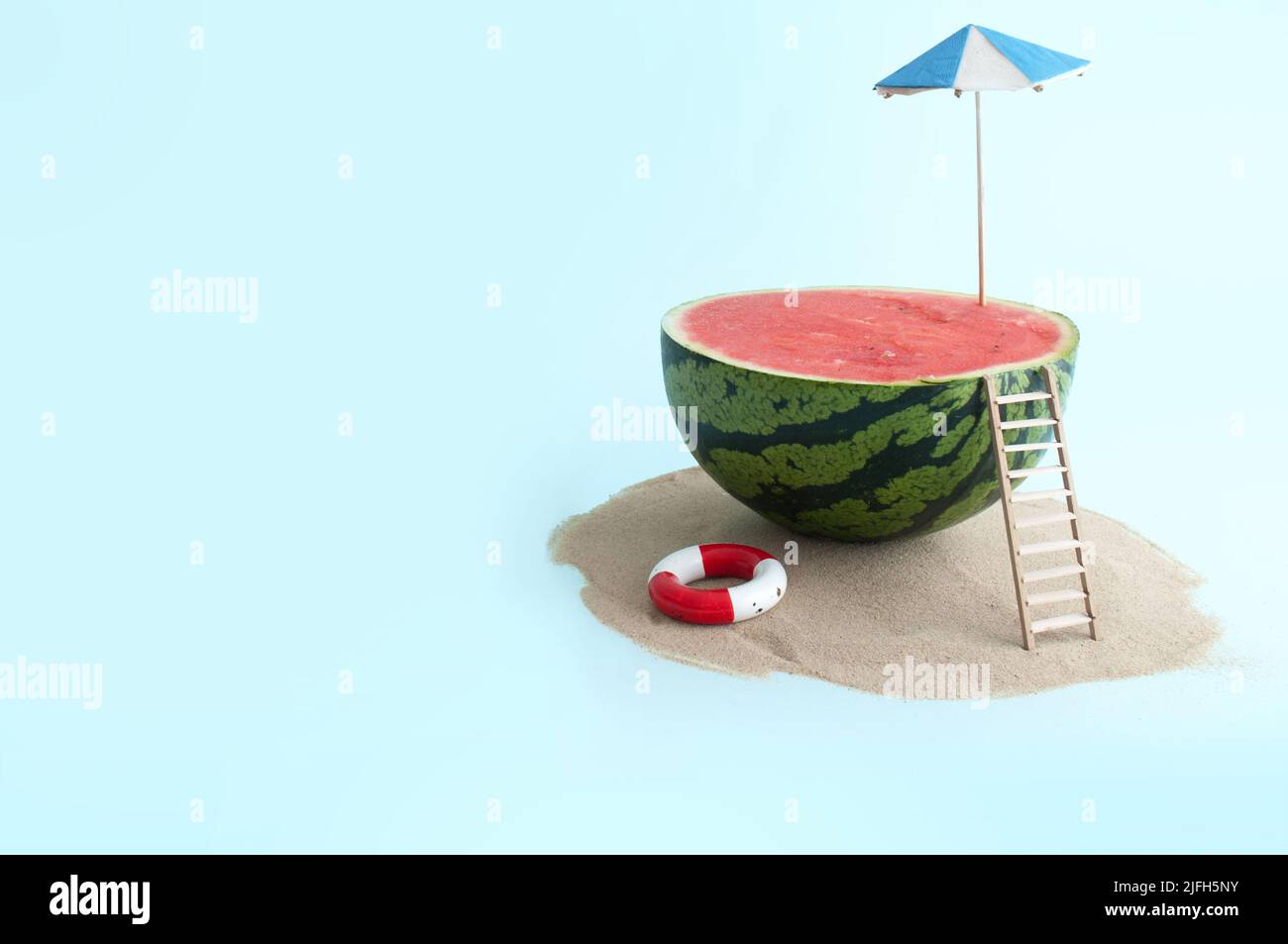 Summer concept, watermelon with parasol and wooden beach ladder Stock Photo