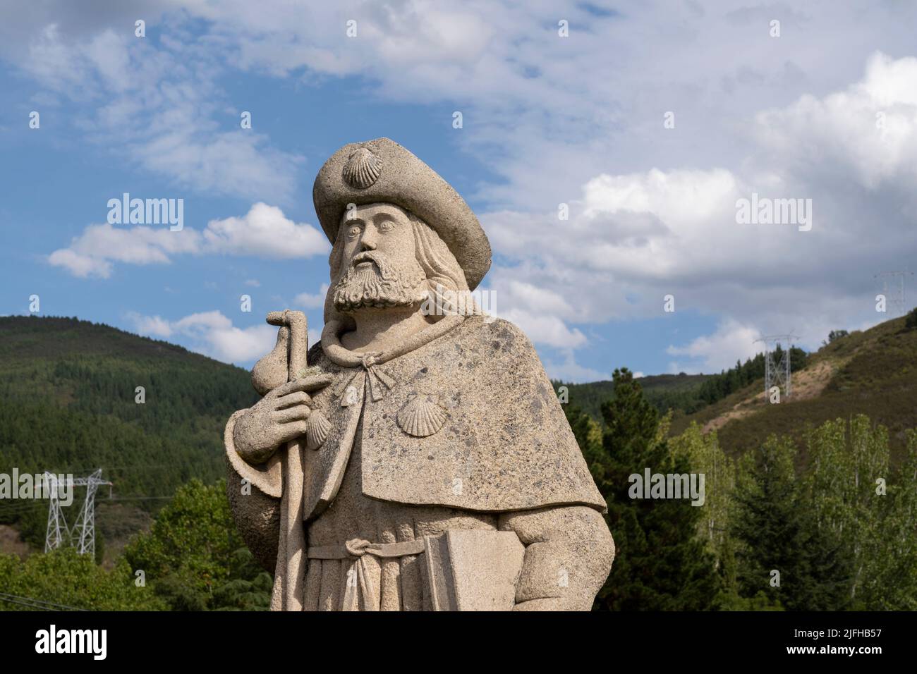Statue of Santiago Peregrino (St James the Great as a pilgrim) shown with customary cloak, scallop shells, staff and gourd along the Camino Frances in Stock Photo