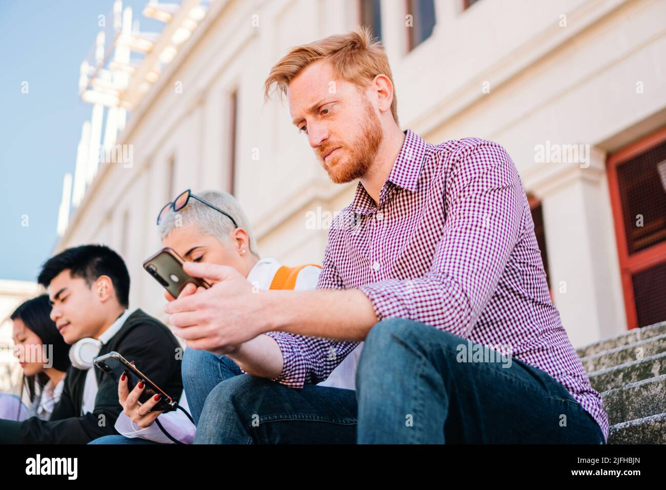 Redhead guy using mobile phone. Joyful unshaven man using mobile phone