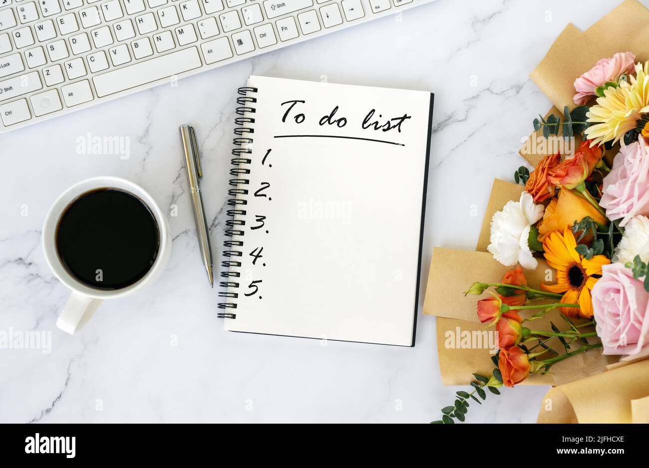 To do list text on note pad on top of office desk with bouquet of