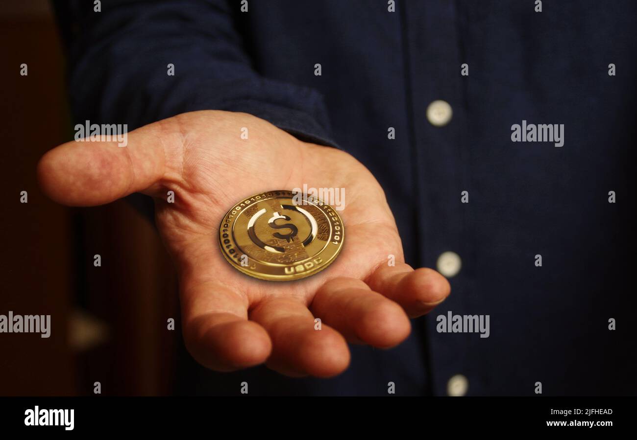 USDC USD Coin stablecoin cryptocurrency golden coin in hand abstract concept Stock Photo
