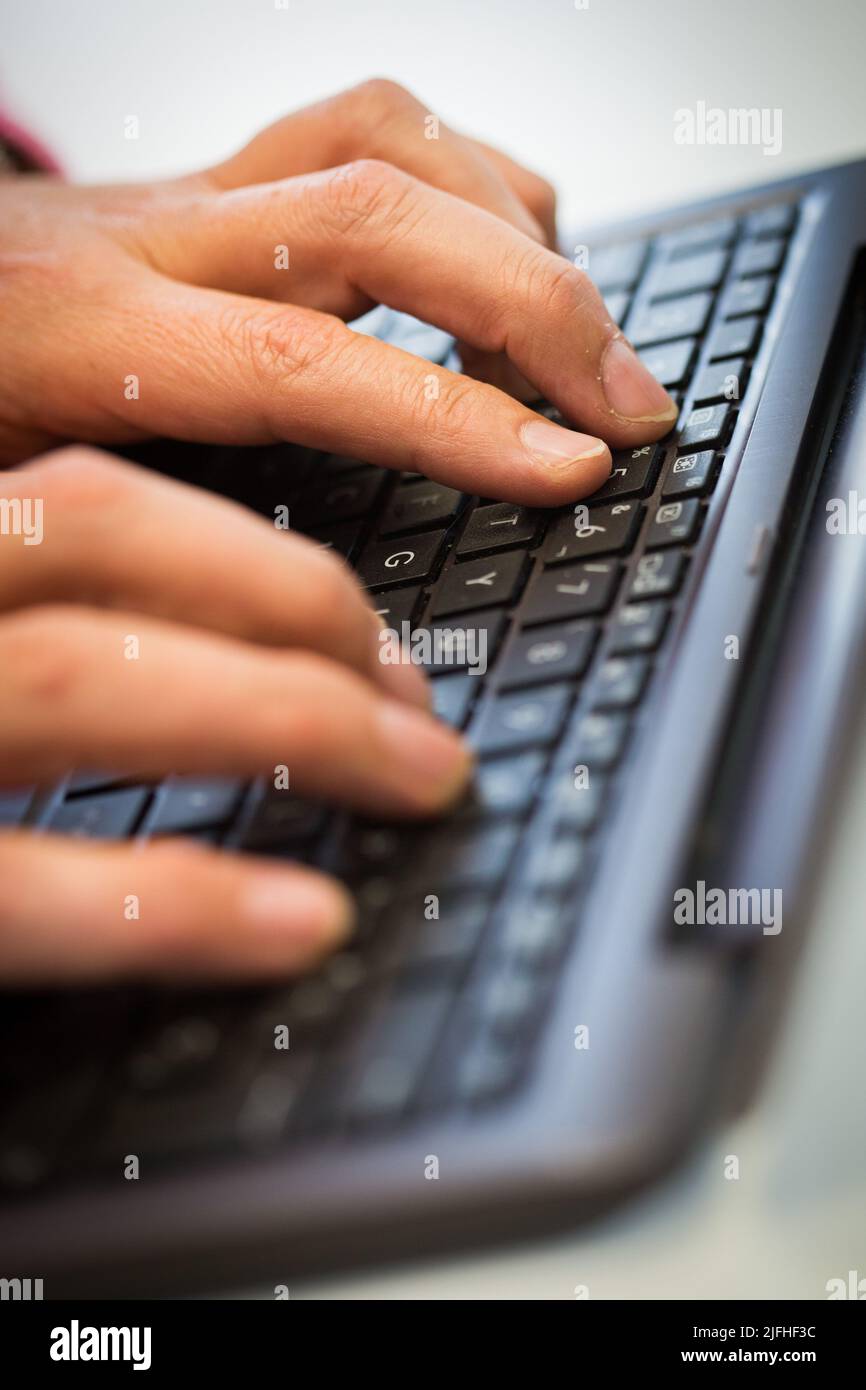 A man's hand typing on a keyboard Stock Photo