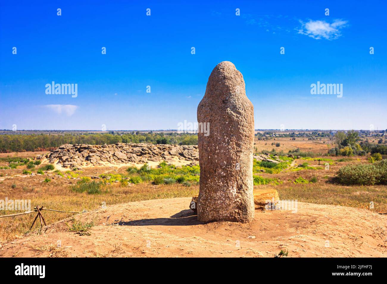 View of the ancient kurgan stela, stone idol against the backdrop of Kamyana Mohylain is an archaeological site in the Molochna River, Zaporizhzhia Ob Stock Photo